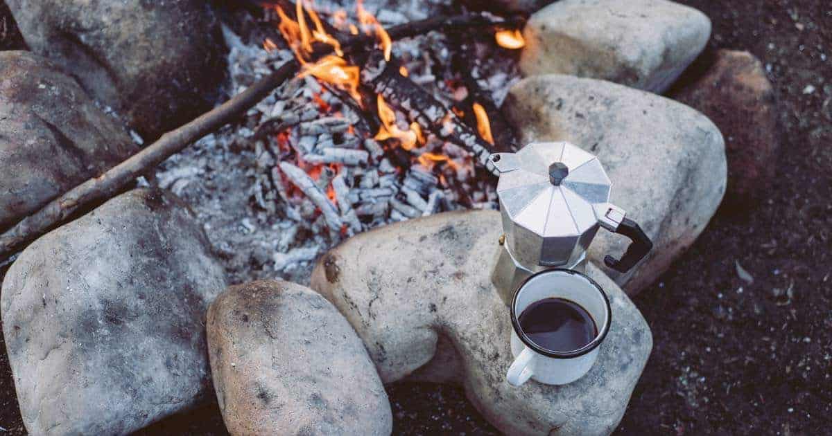 moka coffee maker and mug near open fire