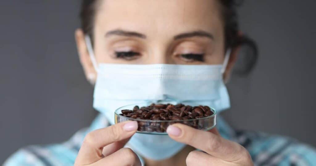 person with mask looking at coffee beans in a petri dish